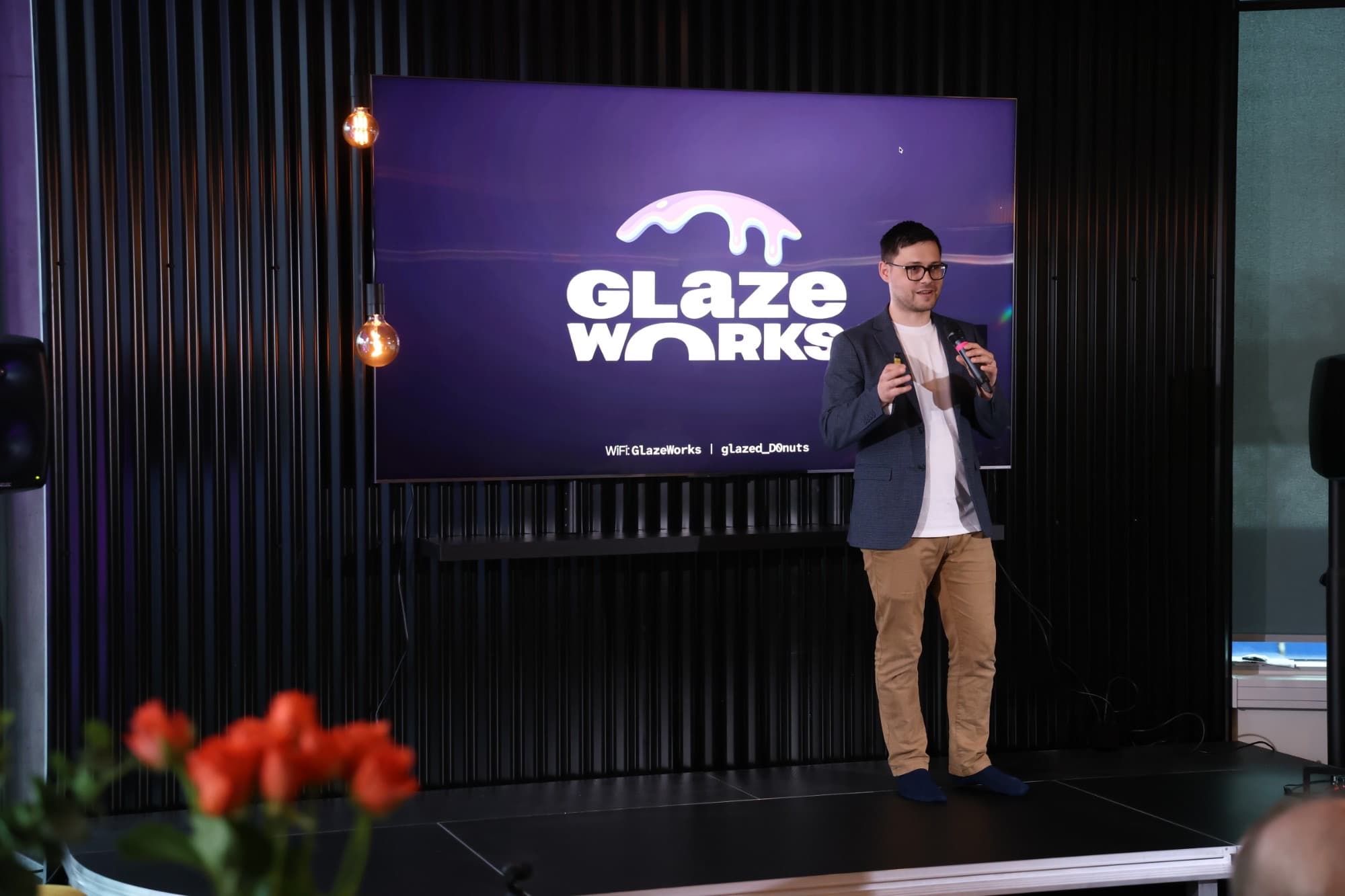 A speaker on stage in front of the Glazeworks screen